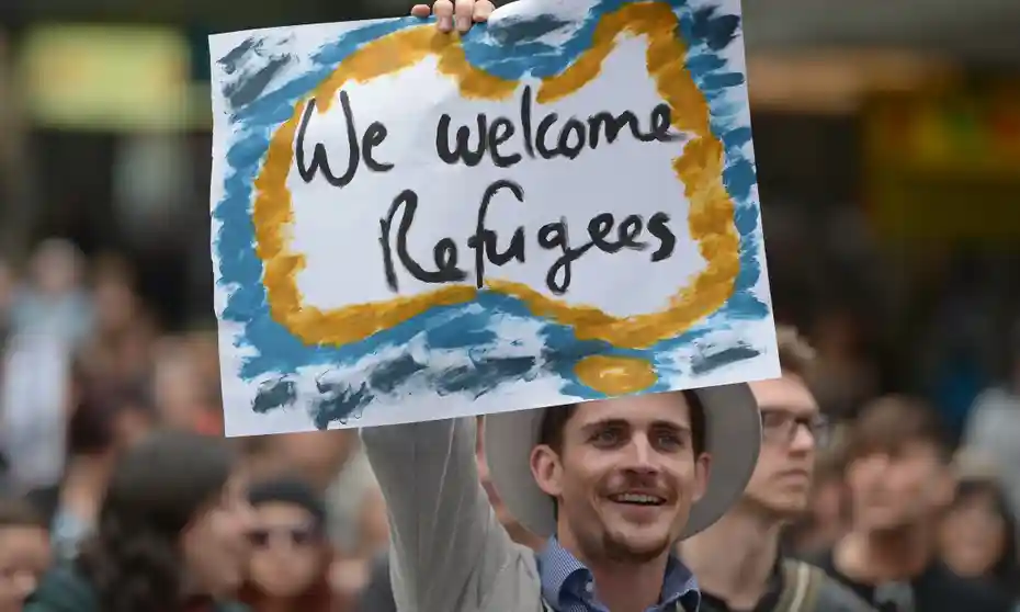 guy holding sign saying welcome refugees